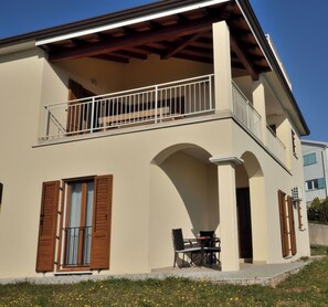 A two-story building with a balcony, a table and chairs outside, and a window with shutters. - Apartment Maria (Labin)