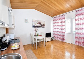 A modern kitchen with a microwave, toaster, and coffee machine. There is a dining area with a table, chairs, and a painting on the wall. - Apartments Buffalo (Primosten)