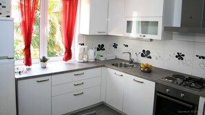 A modern kitchen with white cabinets, a gas stove, a microwave, and a sink. - Apartments Buffalo (Primosten)