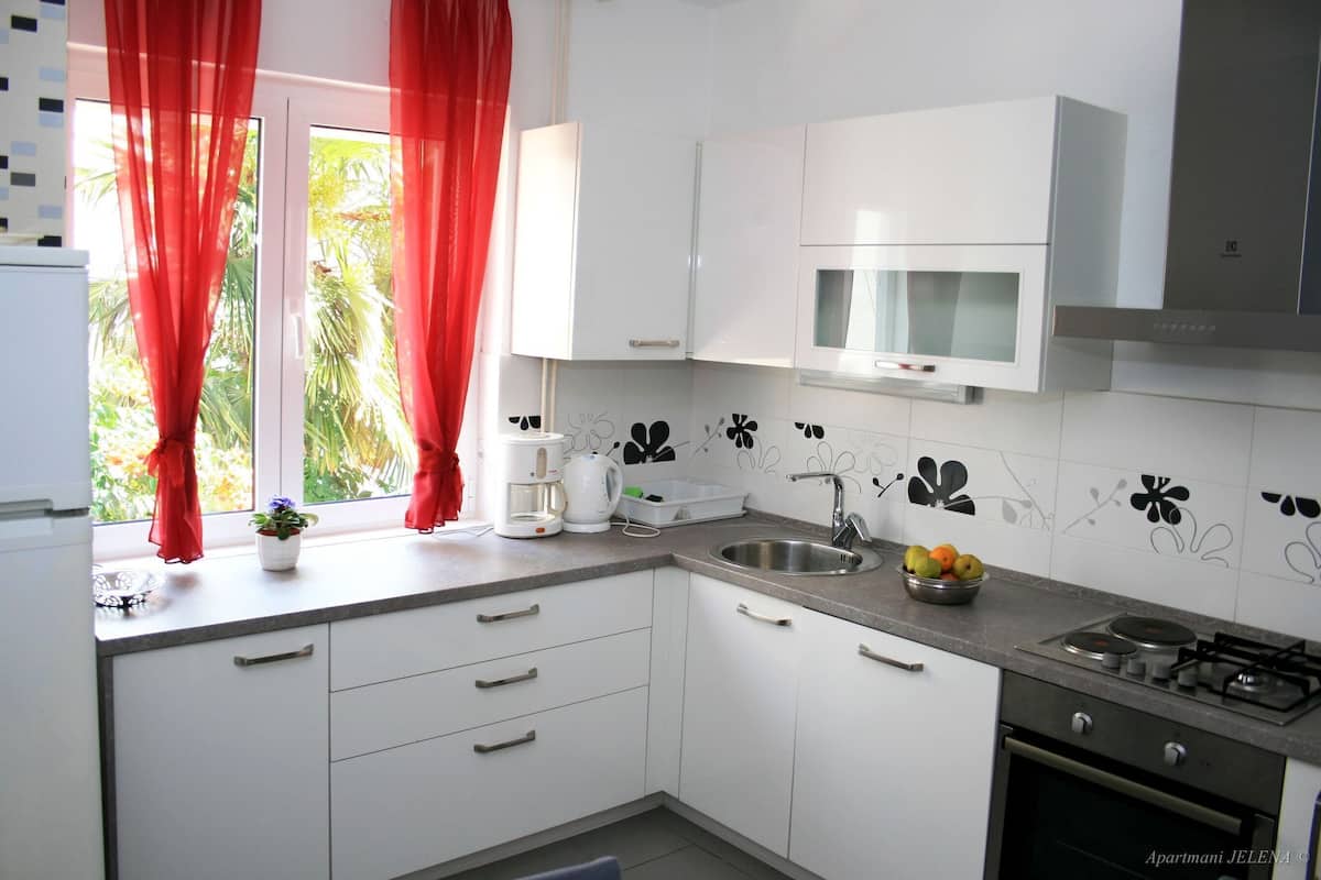 A modern kitchen with white cabinets, a gas stove, a microwave, and a sink.