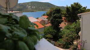 A coastal view with a satellite dish, houses with red roofs, and a mountainous backdrop. - Apartments Buffalo (Primosten)