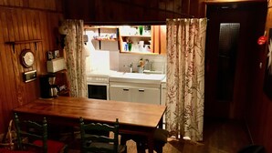 A cozy wooden interior with a dining area, a kitchen visible through an open doorway, and a red chair. - Comfortable family Dupleix mountain view (Orcieres merlette)