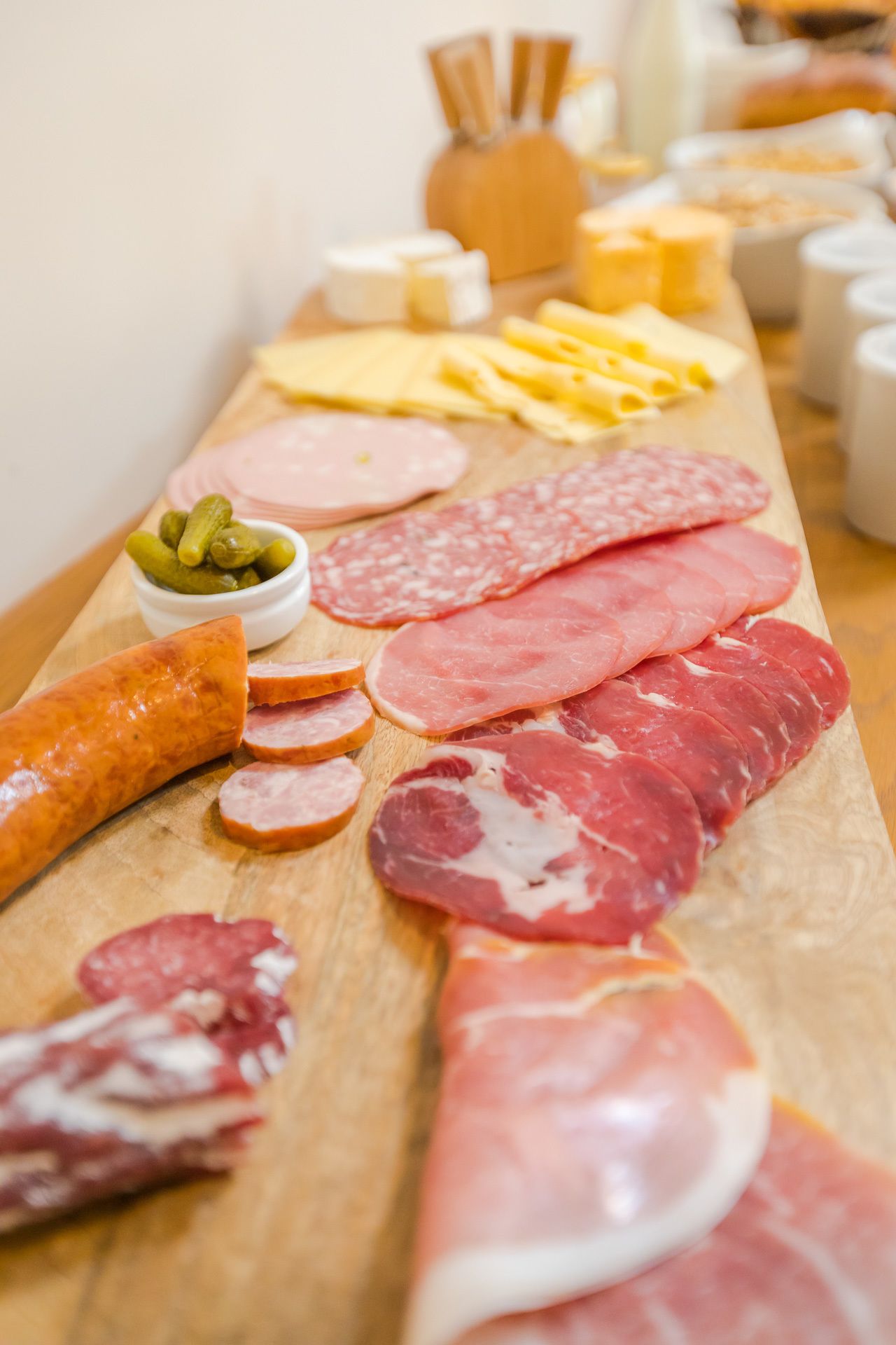 A charcuterie board with various meats, cheeses, and pickles.