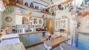 Una cocina rústica con armarios de madera, una mesa de madera y varios utensilios y electrodomésticos de cocina.