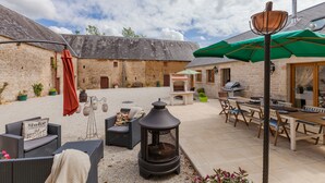 Un patio con mobiliario exterior, una estufa de leña y una zona de barbacoa.
