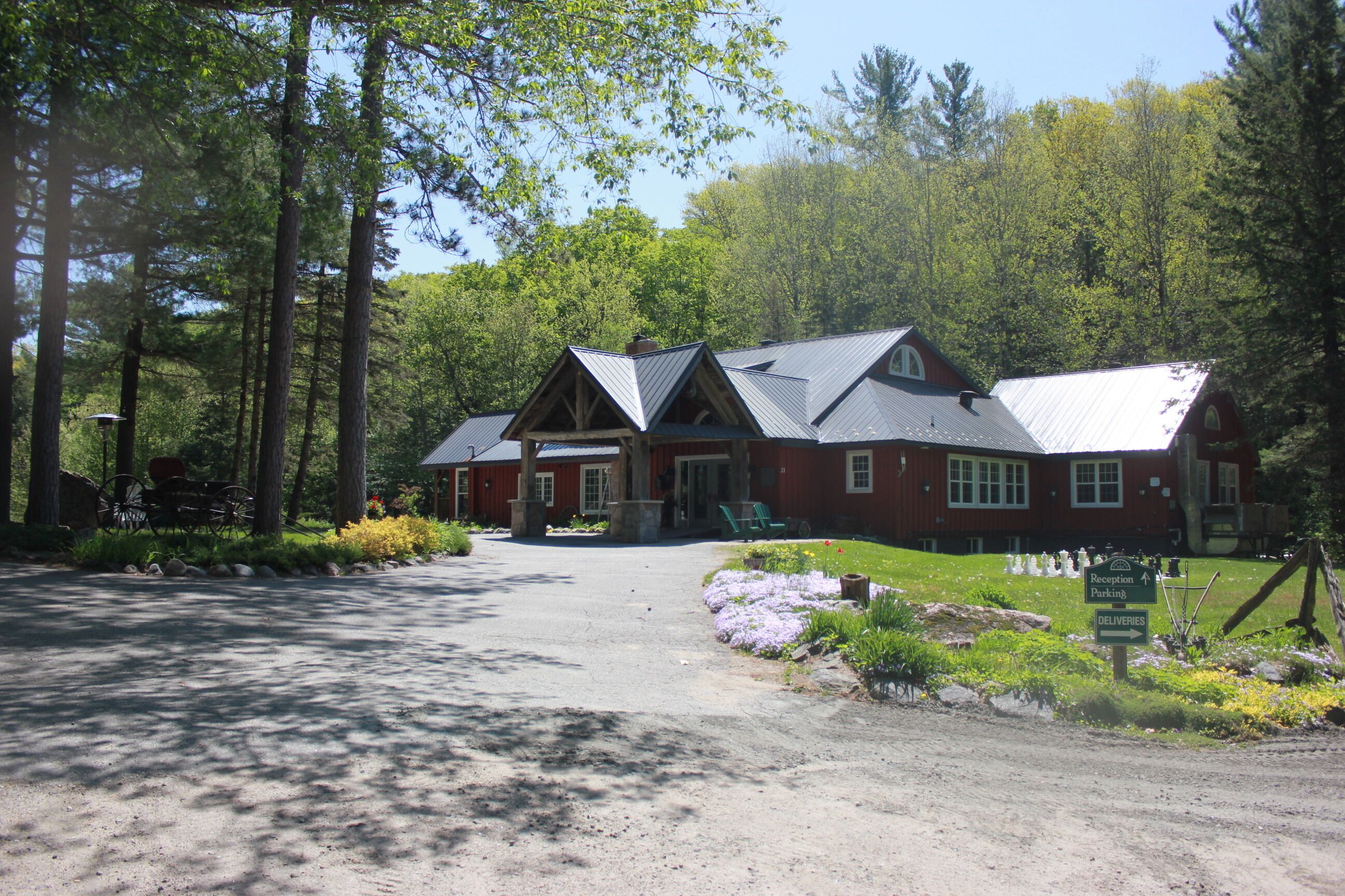 A lodge with a red exterior, a gravel driveway, and a sign indicating reception and delivery areas.