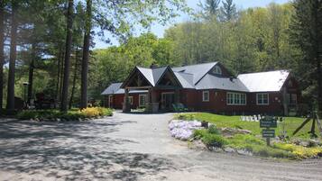 A lodge with a red exterior, a gravel driveway, and a sign indicating reception and delivery areas.