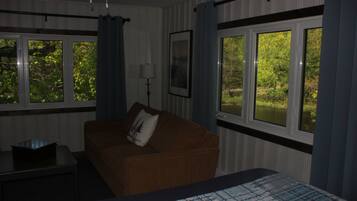 Una habitación con una cama, un sofá marrón, una mesa y ventanas con cortinas.