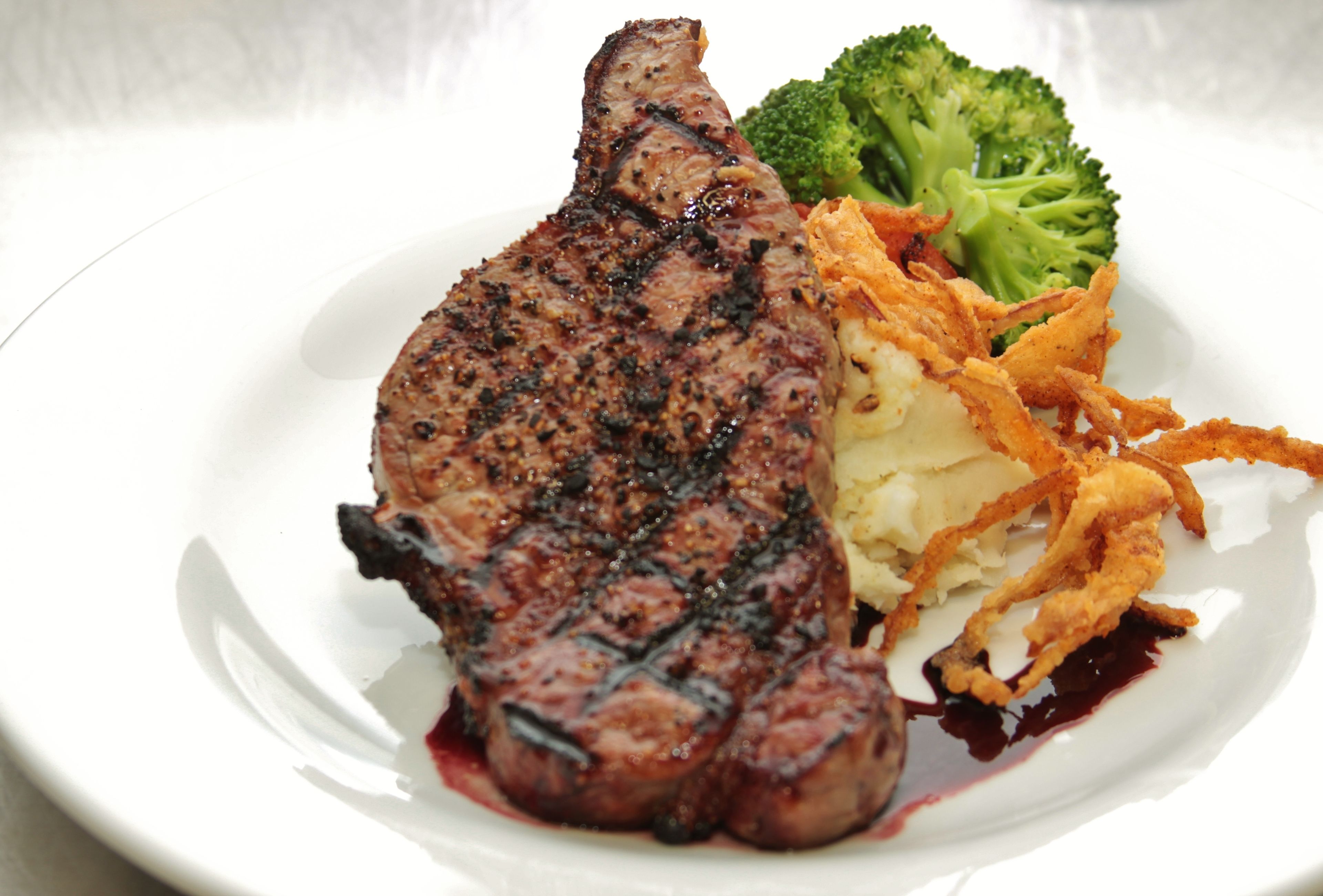 Une assiette comprenant un steak grillé, des brocolis et une portion de purée de pommes de terre.