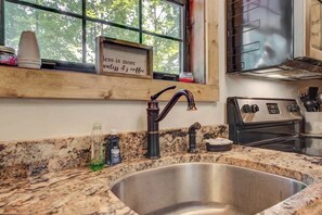 A kitchen with a granite countertop, stainless steel sink, and a stove. - Cozy Cabin w/ Hot Tub & Fireplace | 1 Mile Parkway (Pigeon Forge)