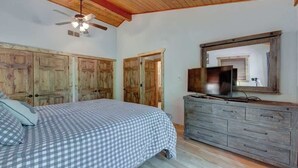 A bedroom with a bed, wooden wardrobe, and a television on a dresser.