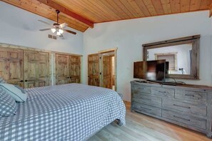 Un dormitorio con cama, armario de madera y televisor sobre un aparador.
