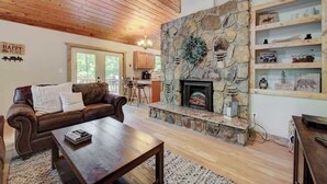 A cozy living room with a stone fireplace, leather sofa, and wooden coffee table.