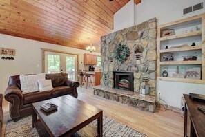 Una sala de estar acogedora con chimenea de piedra, sofá de cuero y mesa de centro de madera.