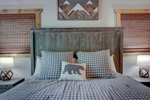 A bed with checkered bedding, a wooden headboard, and two bedside lamps. - Cozy Cabin w/ Hot Tub & Fireplace | 1 Mile Parkway (Pigeon Forge)