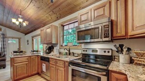 A kitchen with wooden cabinets, a stainless steel stove, a microwave, and a granite countertop.