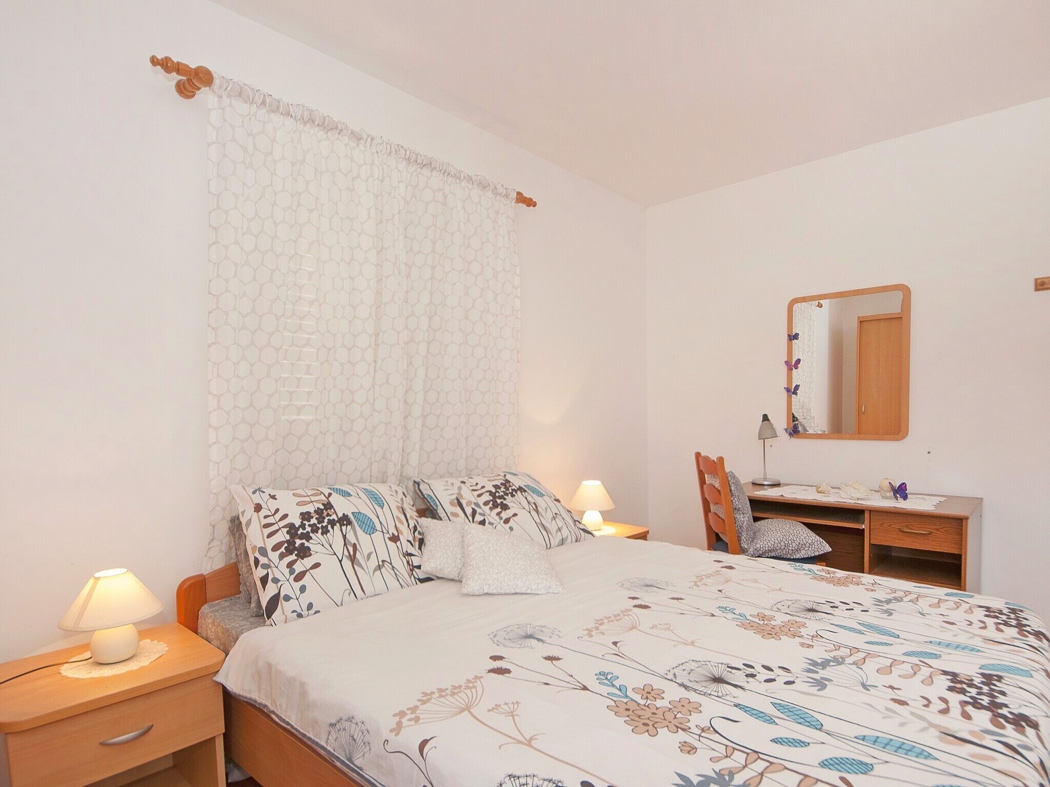 Une chambre à coucher comprenant un lit, une table de chevet, une lampe, un bureau, une chaise et un miroir.