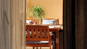 A wooden dining table with a floral tablecloth, a potted plant, and a chair. - Apartments Mara (Supetar)