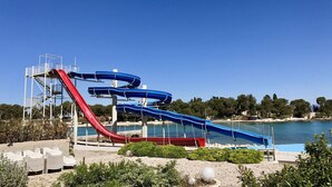 A water park with multiple water slides, a pool, and a beach area with lounge chairs. - House Andelka (Supetar)