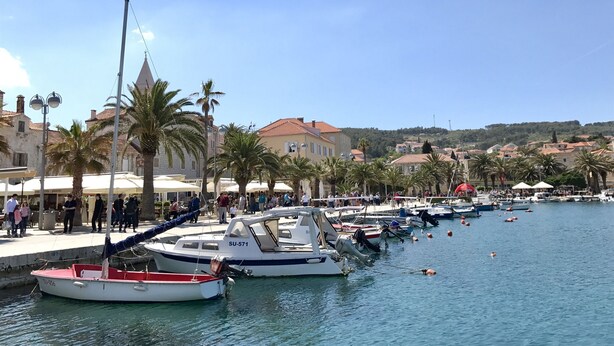 A marina with boats docked, palm trees, and buildings in the background. - House Andelka (Supetar)