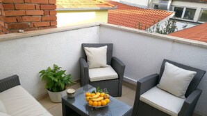 A balcony with wicker furniture, a potted plant, and a fruit bowl. - House Andelka (Supetar)