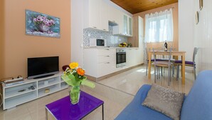 A modern living room with a TV, sofa, and a dining area with a table and chairs. - House Andelka (Supetar)