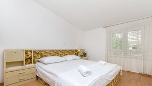 A neatly arranged bedroom with a bed, a nightstand, a dresser, and a window with curtains. - Apartment Neda (Duce)