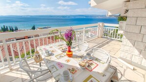 A balcony with a table set for two, overlooking a coastal view. - Apartment Neda (Duce)