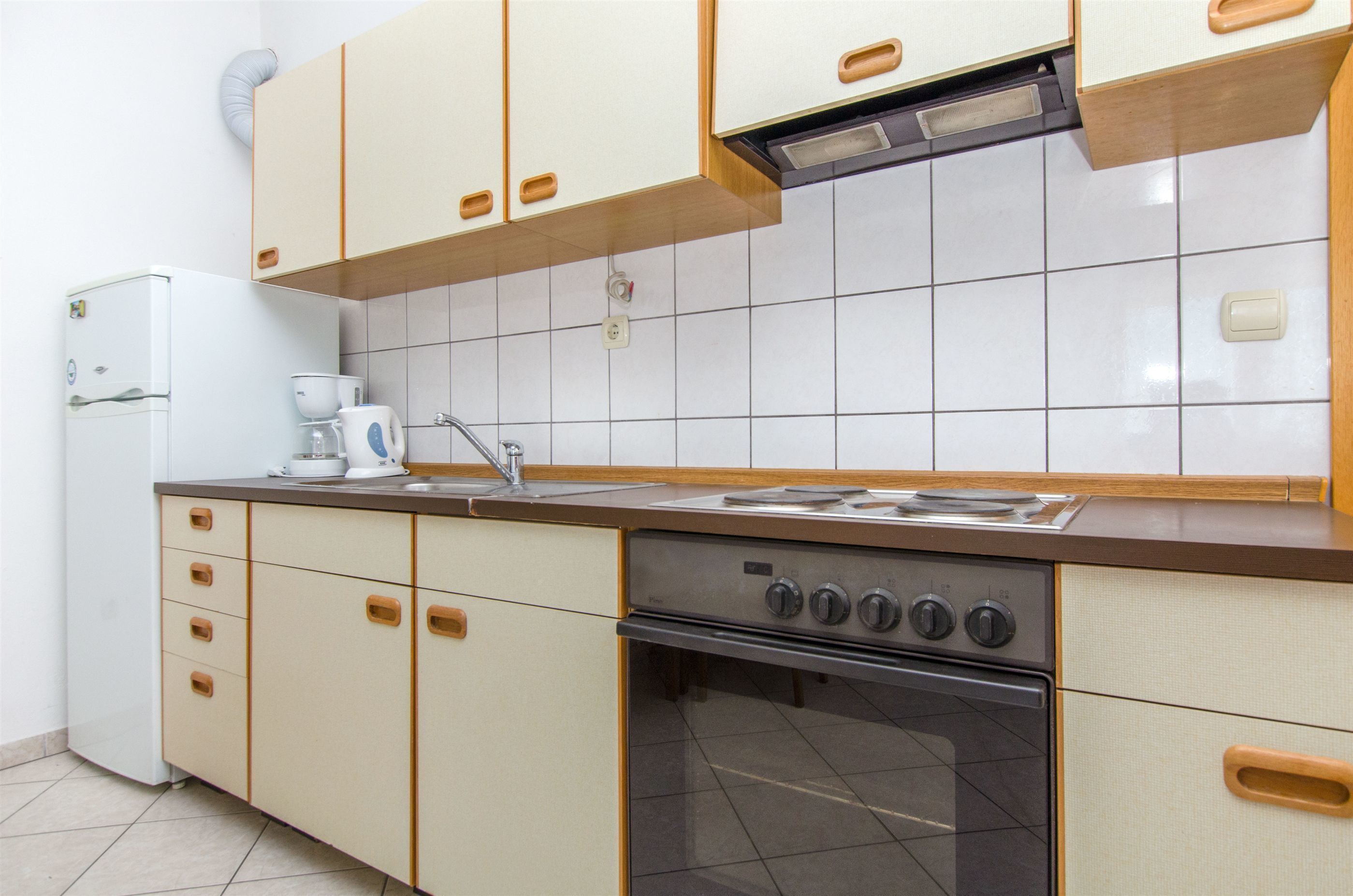 Een keuken met een fornuis, oven en keukenkastjes.