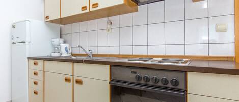 Een keuken met een fornuis, oven en keukenkastjes.