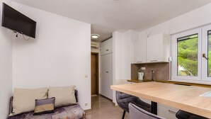 Un espacio habitable compacto con sofá, mesa de comedor y televisor en la pared.