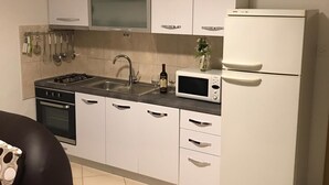 A kitchen with white cabinets, a microwave, a stove, a sink, and a refrigerator. - Apartment Marijana (Trogir)