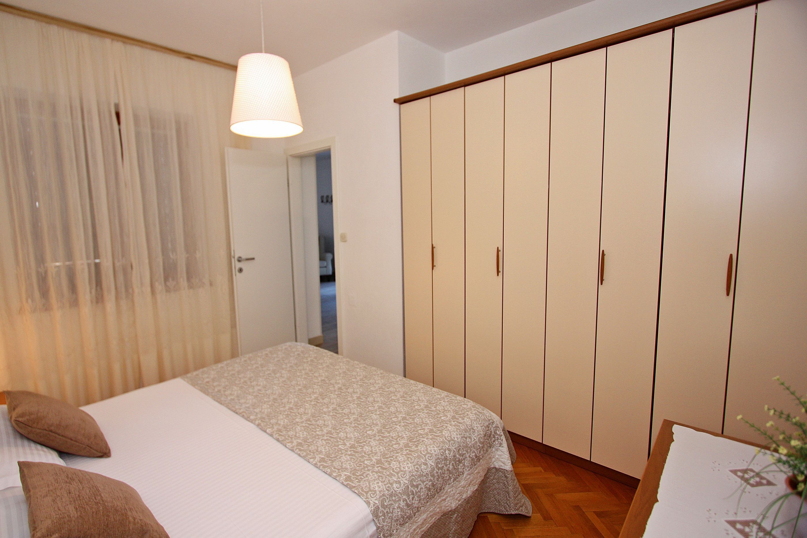 A bedroom with a bed, a wardrobe, and a hanging light fixture.