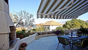 Une terrasse extérieure avec une table et des chaises, une pergola, des plantes en pot et une vue sur une montagne.