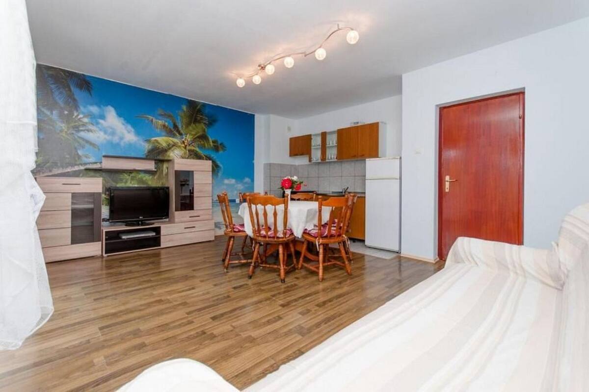 Un espacio habitable compacto con comedor, kitchenette y mueble para televisión.