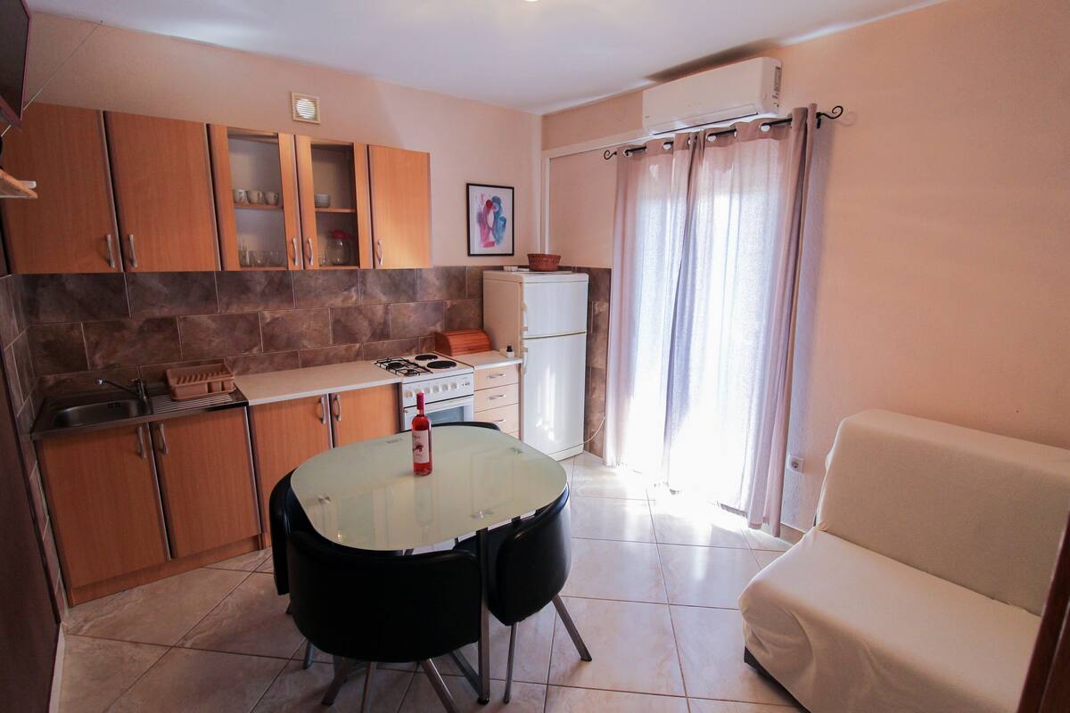 Una cocina compacta con una mesa de comedor, sillas, un sofá y un refrigerador.