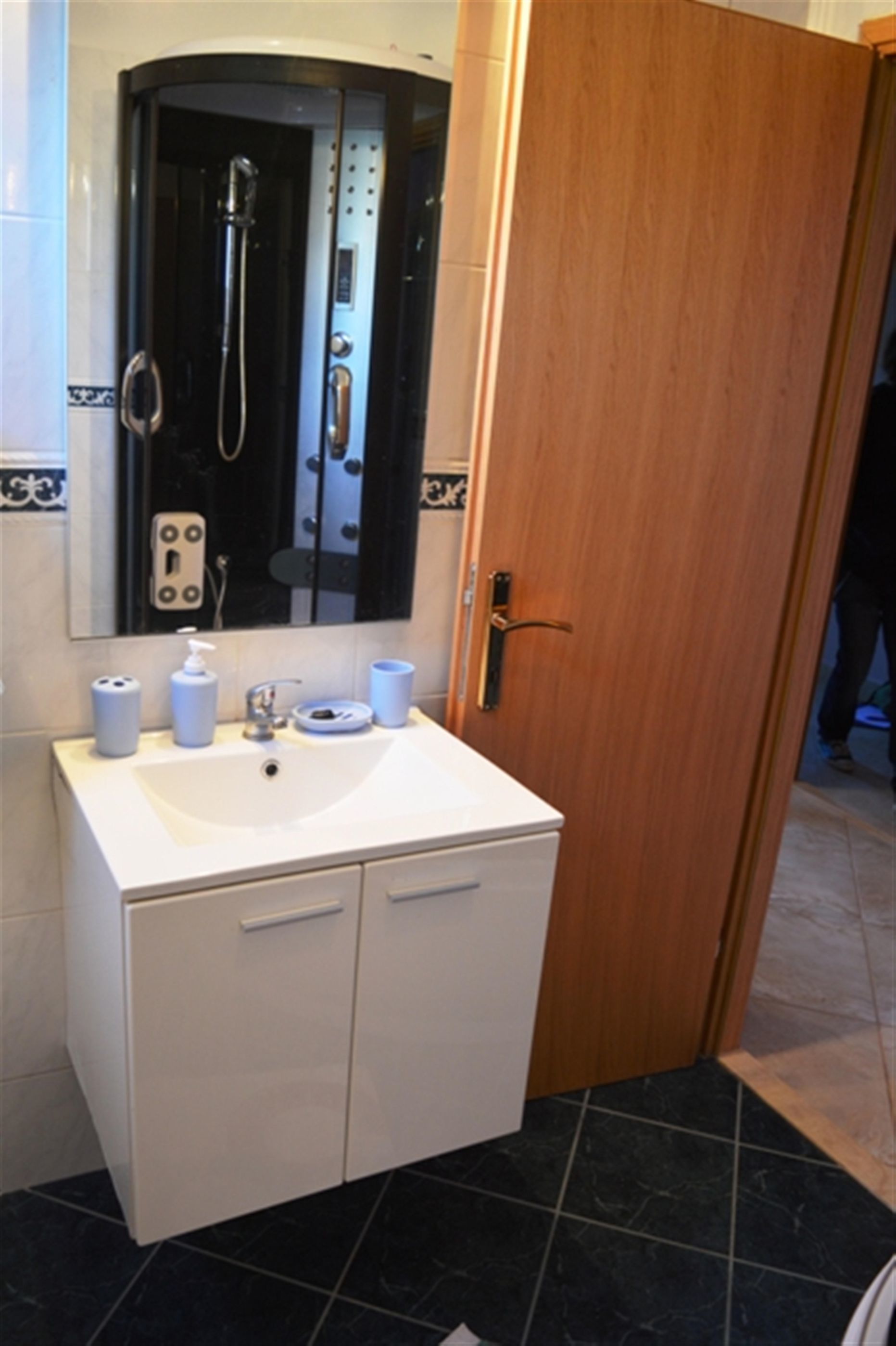 A bathroom with a white sink, mirror, and wooden door.
