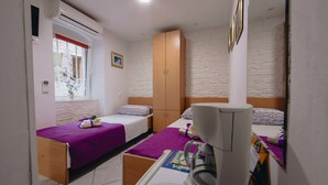 A small, well-lit bedroom with two beds, a wardrobe, an air conditioning unit, and a window with a view. - Apartment and Room Old Town (Split)