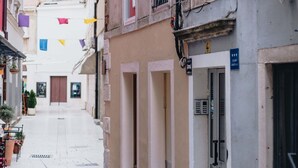 A narrow street with buildings on either side, a manhole cover, and a door with a sign. - Apartment and Room Old Town (Split)