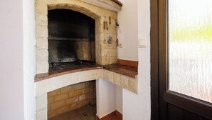 Ein Kamin aus Stein mit Ziegelbasis, eine weiße Wand und ein Fenster zur rechten Seite.