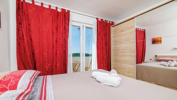 Ein Hotelzimmer mit einem großen Bett, roten Vorhängen, einem Holzschrank und Blick ins Freie.