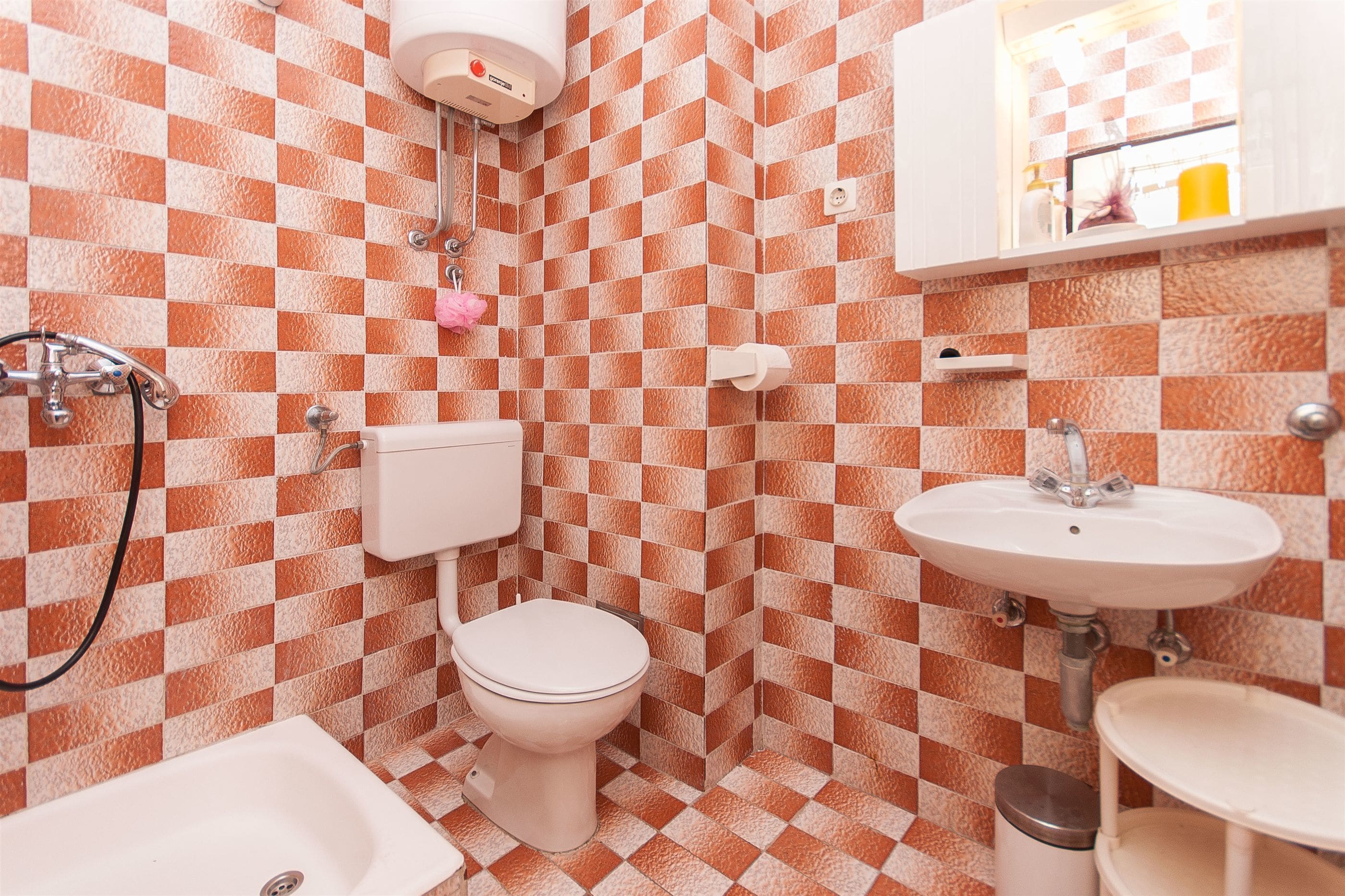 A bathroom with a checkered tile pattern, a toilet, a sink, and a bathtub.