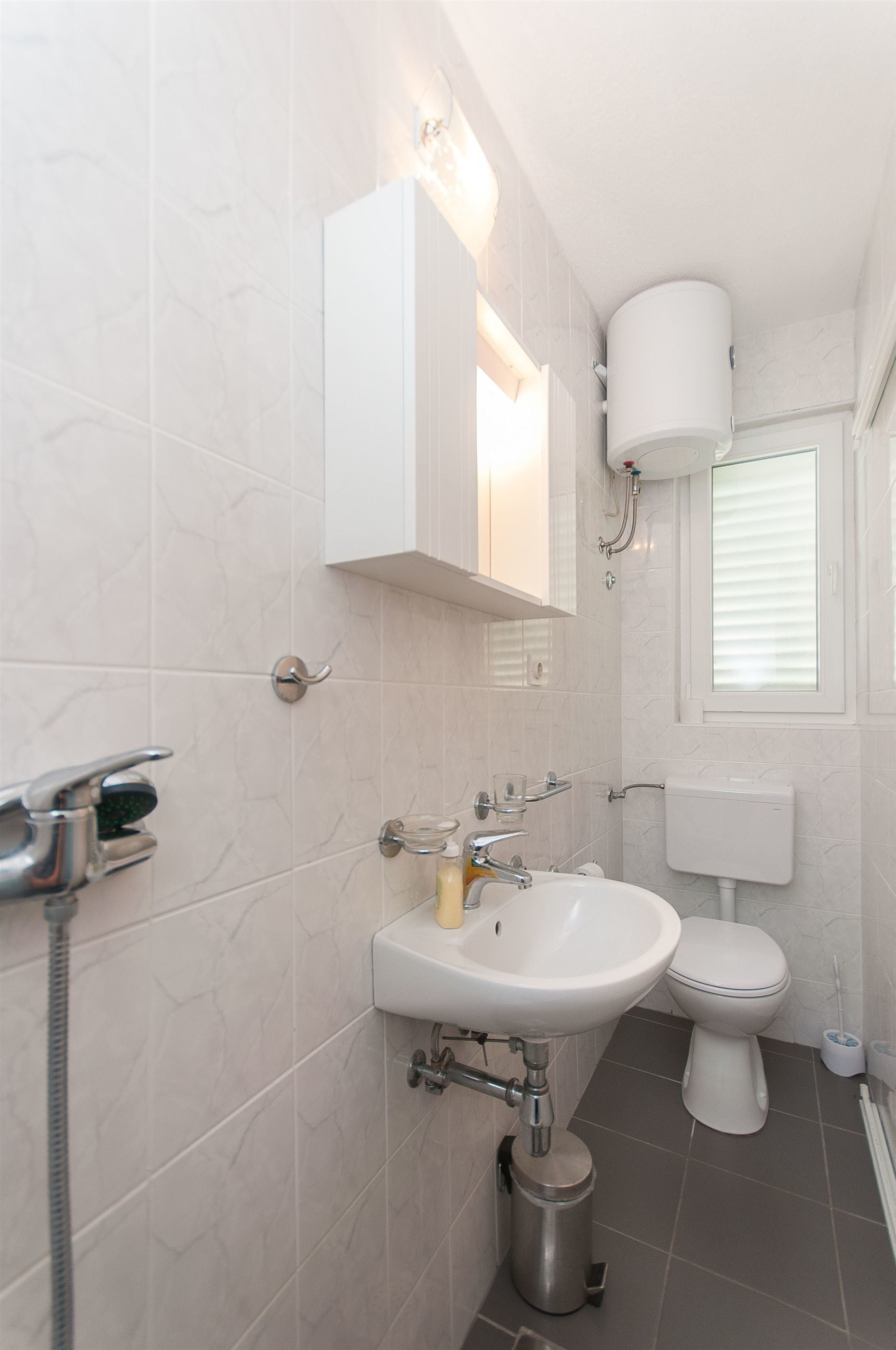 Une salle de bain moderne avec un lavabo, des toilettes et une douche, le tout de couleur blanche.