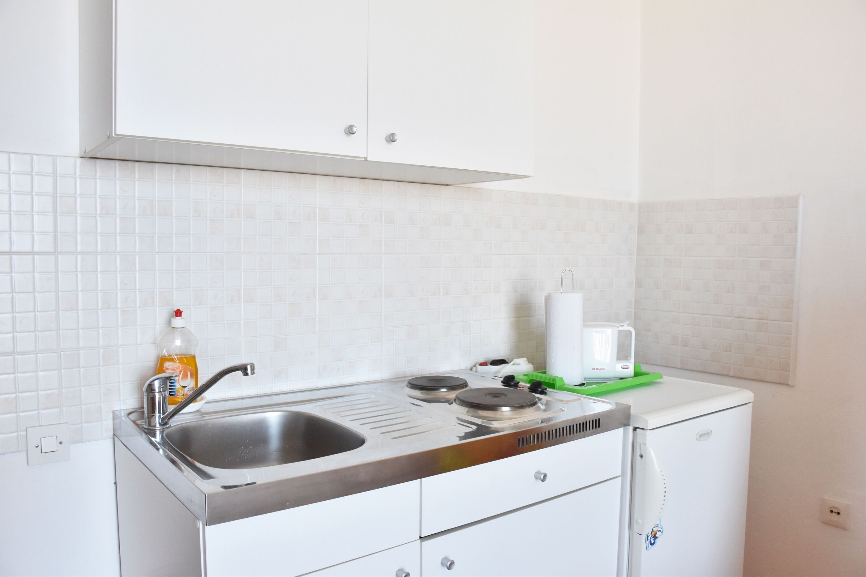 A kitchen with a sink, stove, and a small refrigerator.