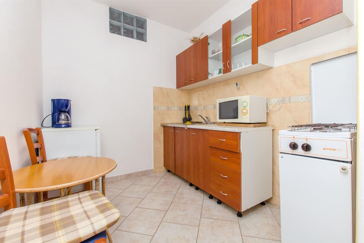 A compact kitchen with a wooden table and chairs, a microwave, a gas stove, and a coffee maker.