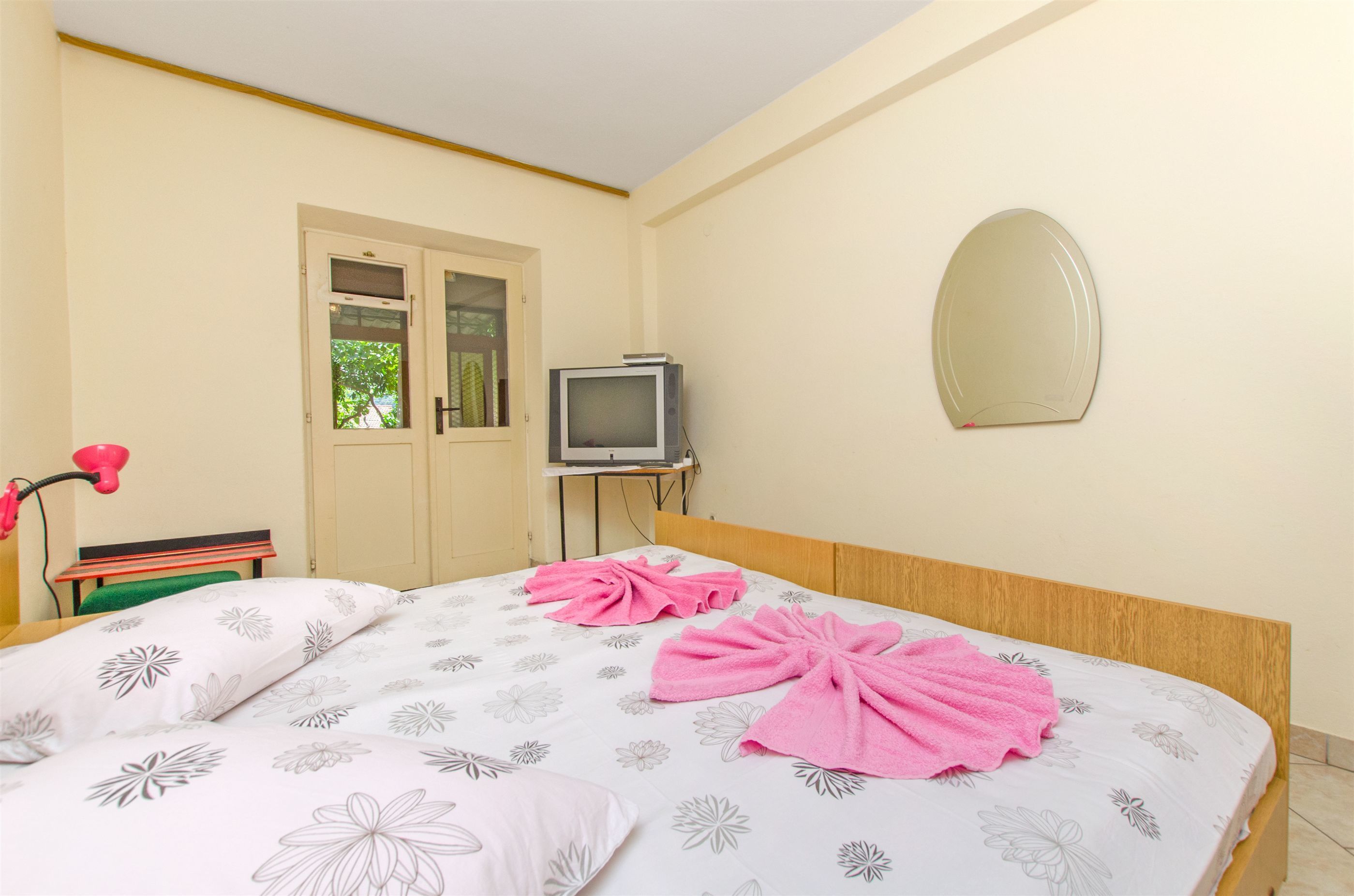 Une chambre d’hôtel avec un lit, une télévision, un miroir et une porte.