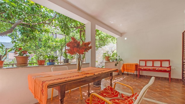 A terrace with a wooden table, chairs, and potted plants. - Apartments Bozjidar (Stari Grad)