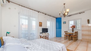 A bedroom with a bed, a desk, a chair, a television, and a dining table with chairs. - Apartments Bozjidar (Stari Grad)
