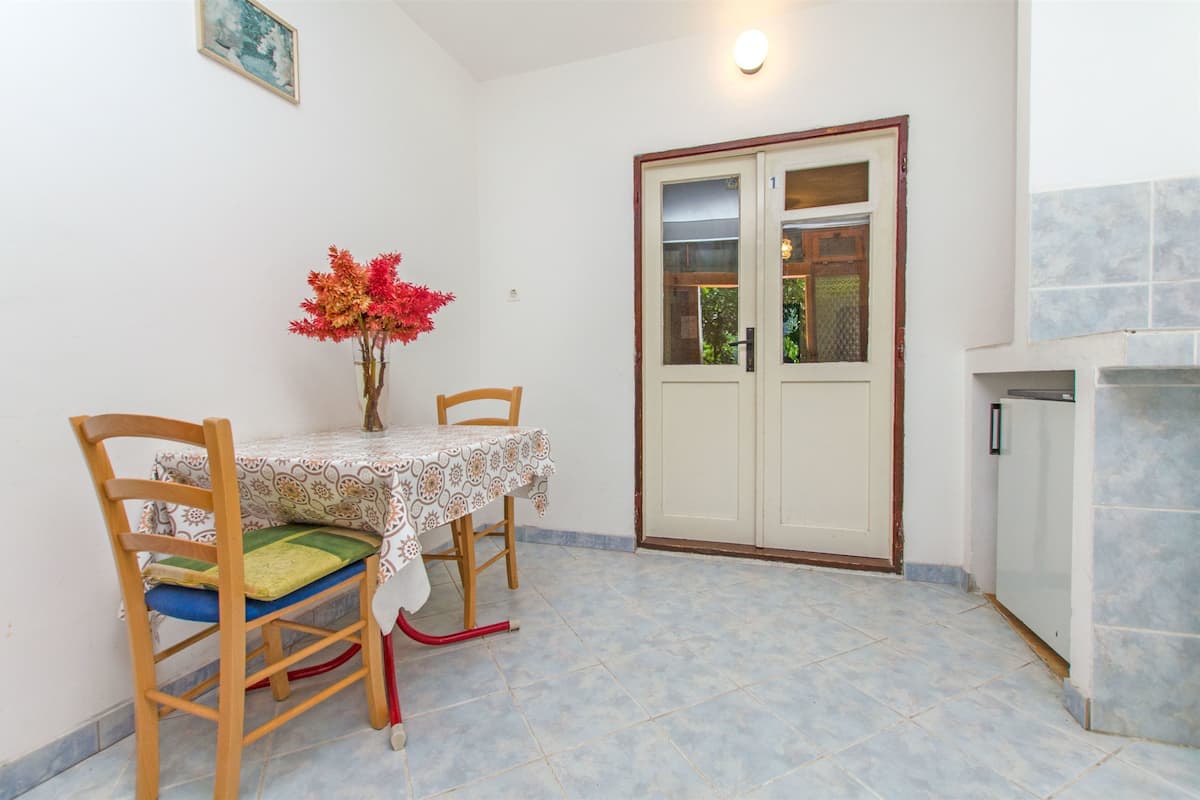 A dining area with a table and chairs, a vase with flowers, and a door with a window.