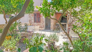 A courtyard with potted plants, a stone wall, and a small seating area with a table and chairs. - Apartments Bozjidar (Stari Grad)